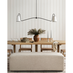 Jonas Linear Chandelier elongated horizontal ceiling light with warm distributed glow above long rectangular dining table in open-plan interior