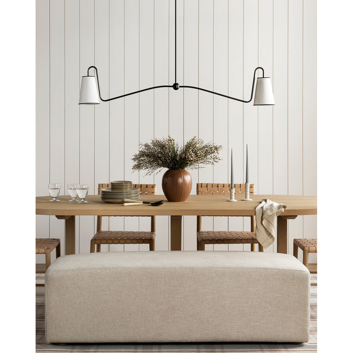 Jonas Linear Chandelier elongated horizontal ceiling light with warm distributed glow above long rectangular dining table in open-plan interior