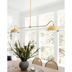 Aldorno linear chandelier with brass finish and round shallow shades.