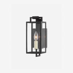 Black forged iron clear glass outdoor wall lantern sconce mounted on a white exterior patio wall with black framed doors and windows.